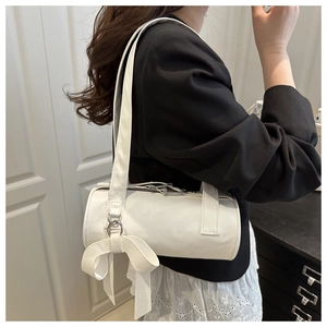 Détail du sac cylindrique blanc avec nœud latéral et texture en similicuir lisse