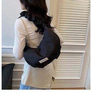 Détail de la bandoulière plissée noire et du sac hobo en croissant avec étiquette