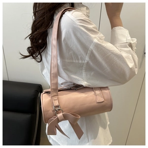 Detailed side view of pink barrel bag on model featuring cute bow charm and sleek strap