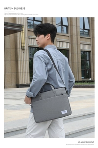 Minimalist grey business laptop bag with adjustable shoulder strap shown in an outdoor city setting