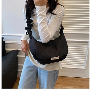 Détail de la bandoulière plissée noire et du sac croissant en nylon sur le modèle