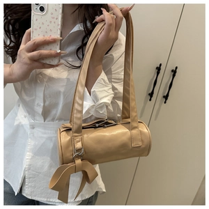 Detail of beige cylinder shoulder bag with side ribbon bow and silver rivets