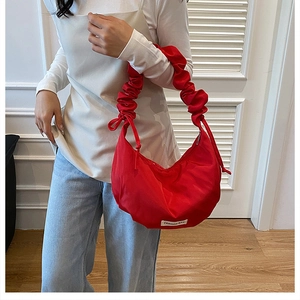 Détail du sac croissant rouge avec bandoulière froncée élégante et étiquette mode