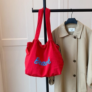 Detailed close-up of a large red canvas tote bag featuring blue Beach text on a hanger