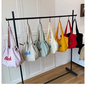 Dettaglio di borse tote in tela in sette colori con coulisse e ricamo Bech su sfondo bianco