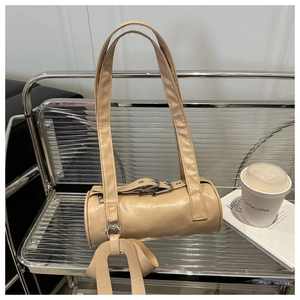 Détail du sac Boston beige avec longues anses et breloque en cuir sur un banc