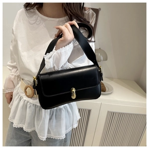 Model wearing black shoulder bag with gold twist lock and adjustable wide strap
