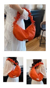 Détail du sac hobo orange avec poignée plissée et forme de croissant en tissu nylon
