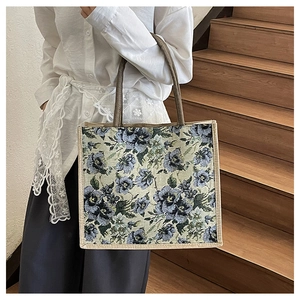 Detail of floral tapestry linen tote bag with brown straps on a rustic wooden background