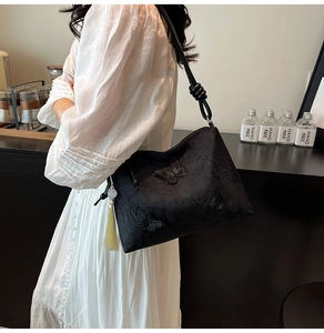 Detail of floral butterfly embroidery and decorative tassel on black tote shoulder bag
