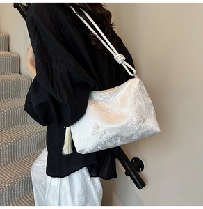 Detail of white tote bag featuring exquisite butterfly embroidery and tassel charm