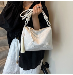 Detail of white butterfly embroidery and silk tassel on elegant vegan leather tote bag