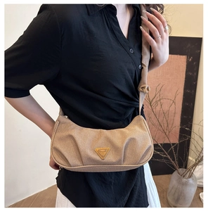 Close-up of khaki pleated crescent bag with textured fabric and triangular logo