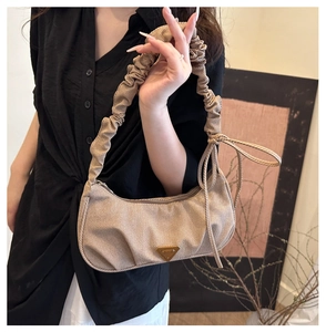 Detail of ruched handle and side ribbon bow on khaki fabric underarm bag with metal logo
