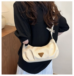 Chic beige ruched hobo bag shown from a side view on a model in a cozy interior setting