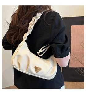 Detail of a beige crescent hobo bag featuring a ruched shoulder strap and triangle logo