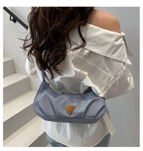 Blue pleated hobo bag with gold triangle logo detail worn on the shoulder by a model