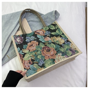 Detailed close-up of colorful floral embroidery on a large linen tote bag on a bed