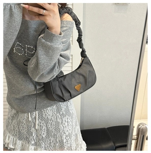 Mirror selfie showing the dark grey pleated nylon bag with a gold triangular metal logo