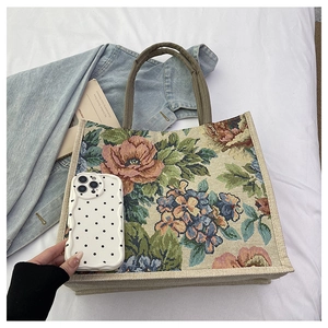 Detail view of linen tote bag featuring vintage floral embroidery and woven straps