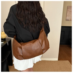 Detail view of large brown soft leather hobo bag with pleated texture on model back