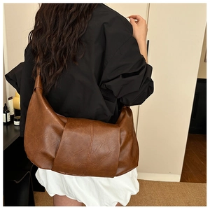 Detail of a brown leather crescent dumpling bag with decorative stitching on the back