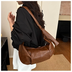 Detail of the caramel brown crescent bag with a knotted strap and leather texture