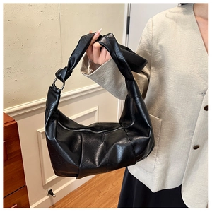 Detail of black pleated hobo bag with knotted strap and metal ring buckle decoration