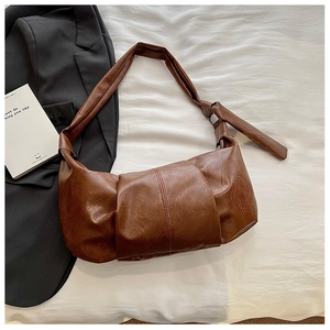 Detail of soft brown pleated croissant bag with a stylish knotted shoulder strap detail