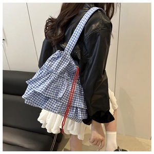 Detail of blue gingham tote bag with layered ruffles and red drawstring accents