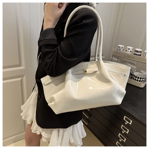 Detail of white patent leather tote bag with pleated texture and gold metal buckle closure