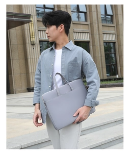 Gray canvas laptop bag with durable handles and side label in a modern outdoor setting