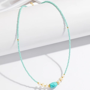 Elegant beaded necklace with turquoise stone and freshwater pearls on white pedestal
