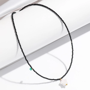 Baroque black faceted bead necklace with white star pearl pendant and green accent bead