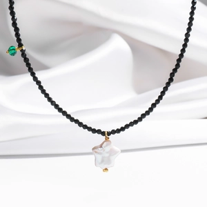Detail of beaded necklace with black faceted beads and a white star pearl pendant