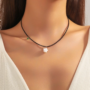 Baroque freshwater pearl necklace with black beads and a white star pendant on a model