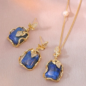 Vintage jewelry set with blue gemstone earrings and pearl necklace in gold leaf design