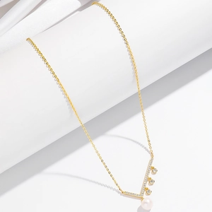 Détail du collier en or avec pendentif en V serti de diamants et perle d'eau douce