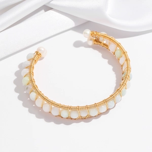 Detail of handcrafted gold wire wrapped open bangle with white pearls and jade beads