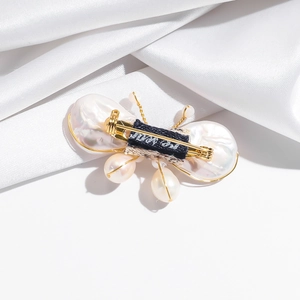 Elegant butterfly brooch with baroque freshwater pearls and gold wire on white silk
