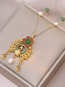Detailed close-up of peacock enamel pendant with fresh pearls on purple silk fabric