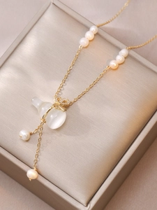 Detail of gold necklace with opal bag pendant and white pearls on champagne jewelry box