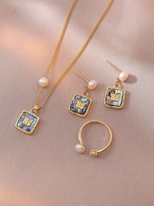 Detail view of butterfly shell jewelry set with pearls on elegant golden satin fabric