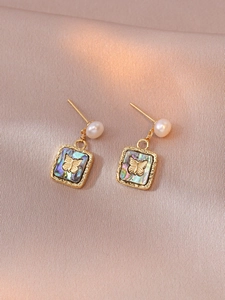 Detailed view of gold square butterfly earrings with iridescent shell inlay and pearl studs