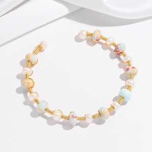 Detailed macro of handmade gold wire-wrapped bracelet with pearls and colorful beads