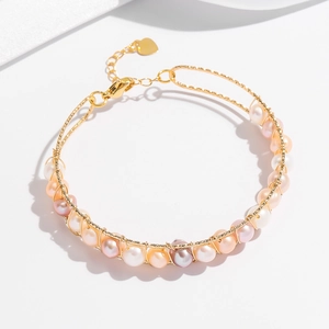 Detail of natural pearls wrapped in gold wire with a heart charm on the bracelet