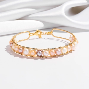 Detail of handmade gold wire-wrapped bracelet featuring colorful freshwater pearls