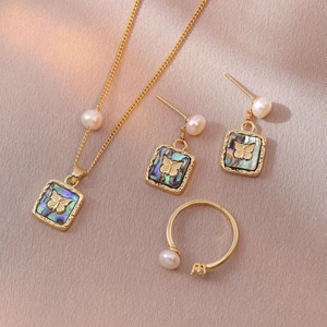 Elegant gold butterfly jewelry set with pearl necklace, earrings and open ring on silk