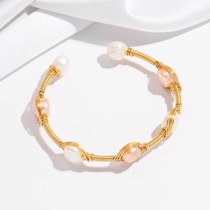 Close-up of gold wire-wrapped open bangle with natural white and pink baroque pearls