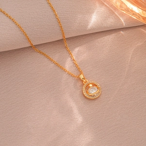 Collana con pendente pianeta stella, catena dorata e zircone su tessuto rosa